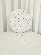 Balon decorativ textil din bumbac alb cu imprimeu floral si panglici, asezat pe un patut pentru copii.