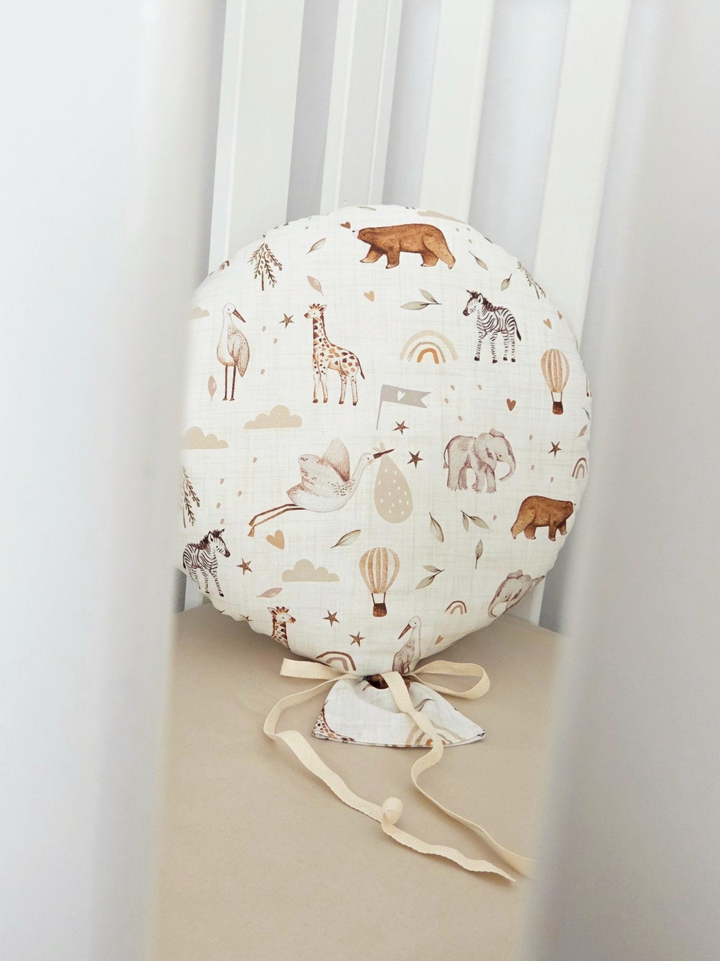 Balon decorativ textil din bumbac alb cu imprimeu floral si panglici, asezat pe un patut pentru copii.
