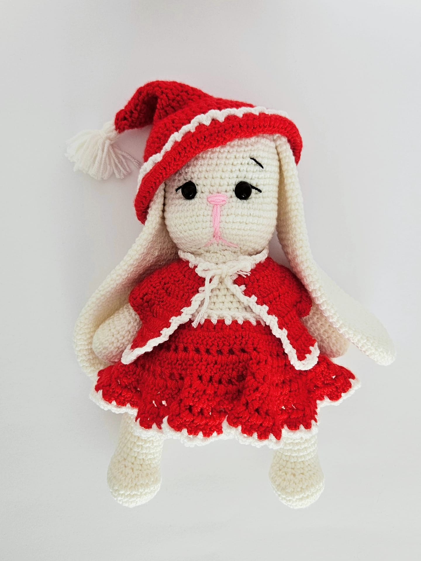 Iepuras crosetat handmade din bumbac alb si rosu, imbracat in rochita si caciulita rosie cu detalii albe.